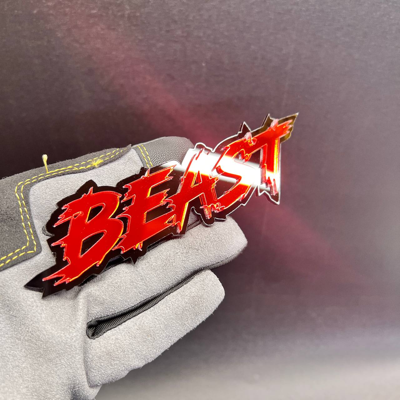 Layered BEAST car badge with bold red lettering and jagged black outline