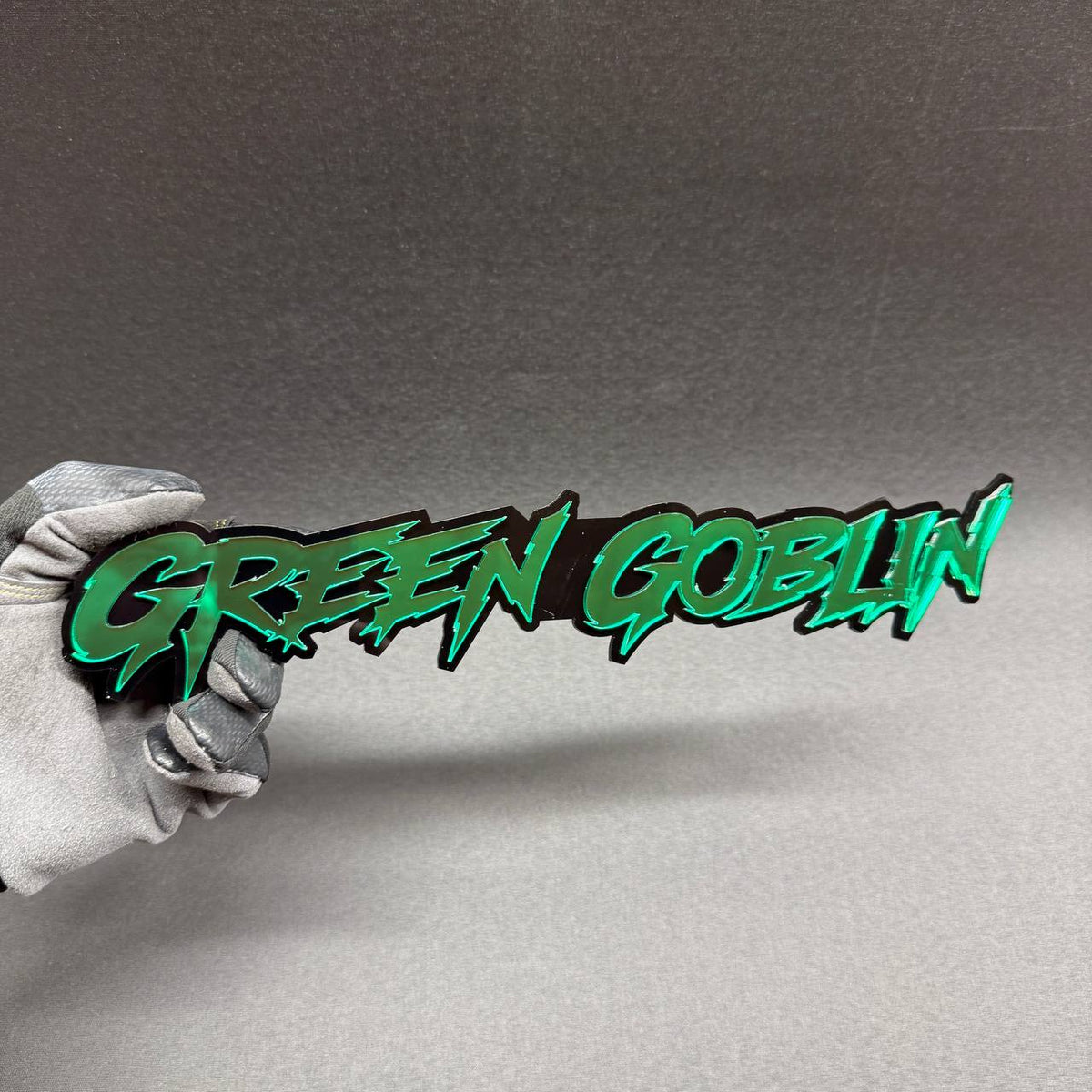 Green Goblin custom grille badge with sharp graffiti inspired lettering, superhero themed exterior accessory for Jeep Wrangler, Gladiator and custom off-road vehicles.