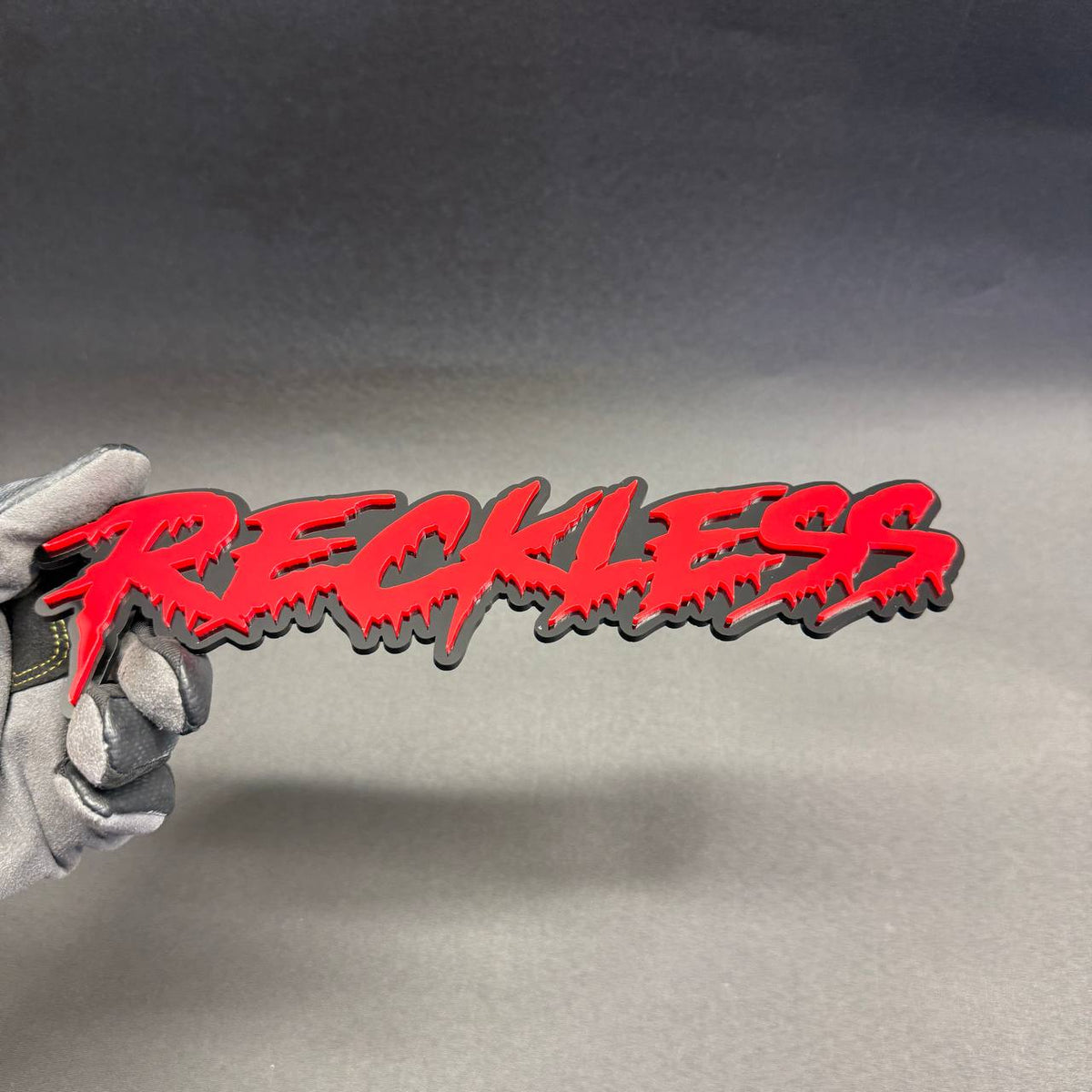 Reckless red dripping graffiti script badge with glossy black background for Chevrolet Camaro Corvette performance car styling.