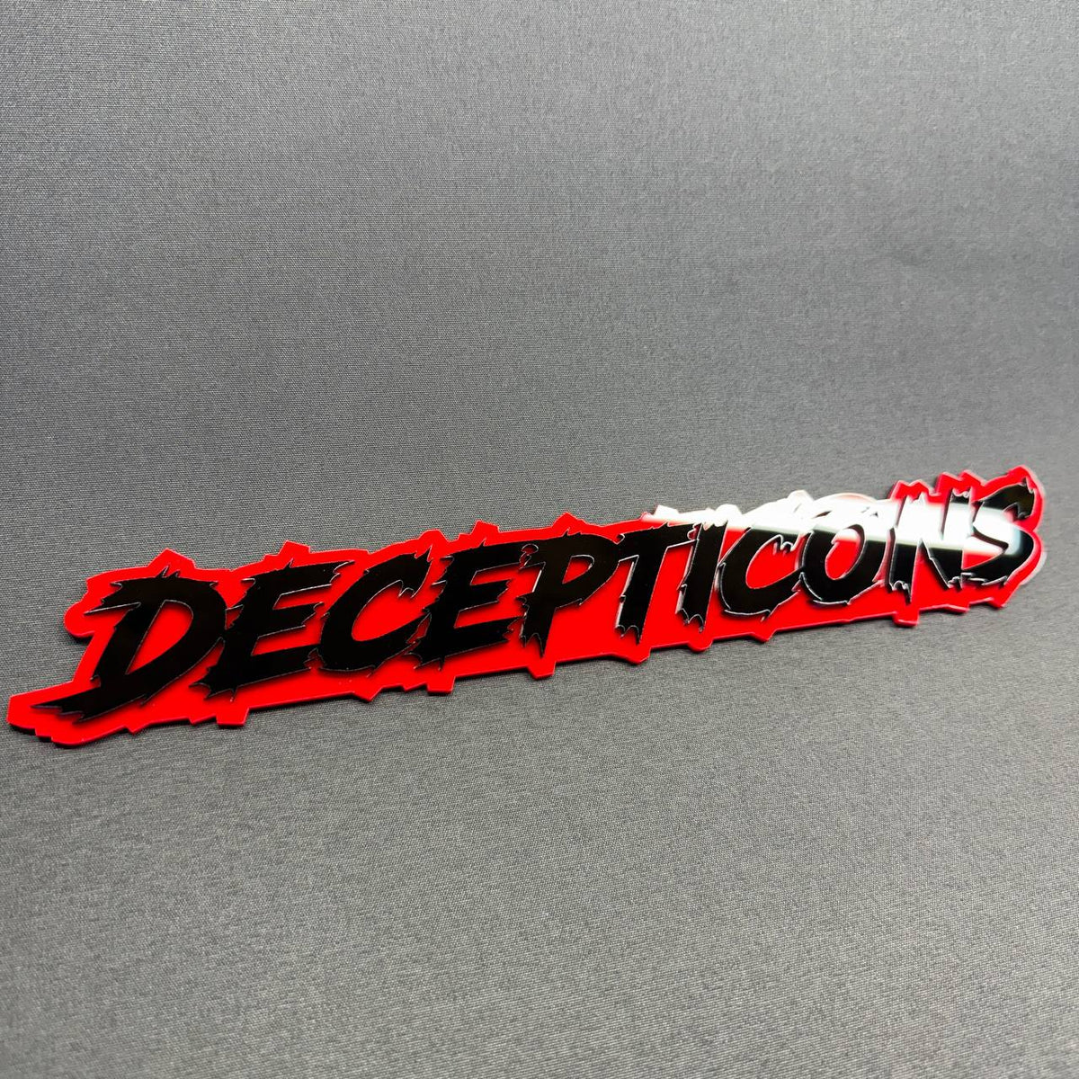 Transformers Decepticon text truck badge with jagged black typography, layered red background and custom styling for Ford Bronco Raptor.