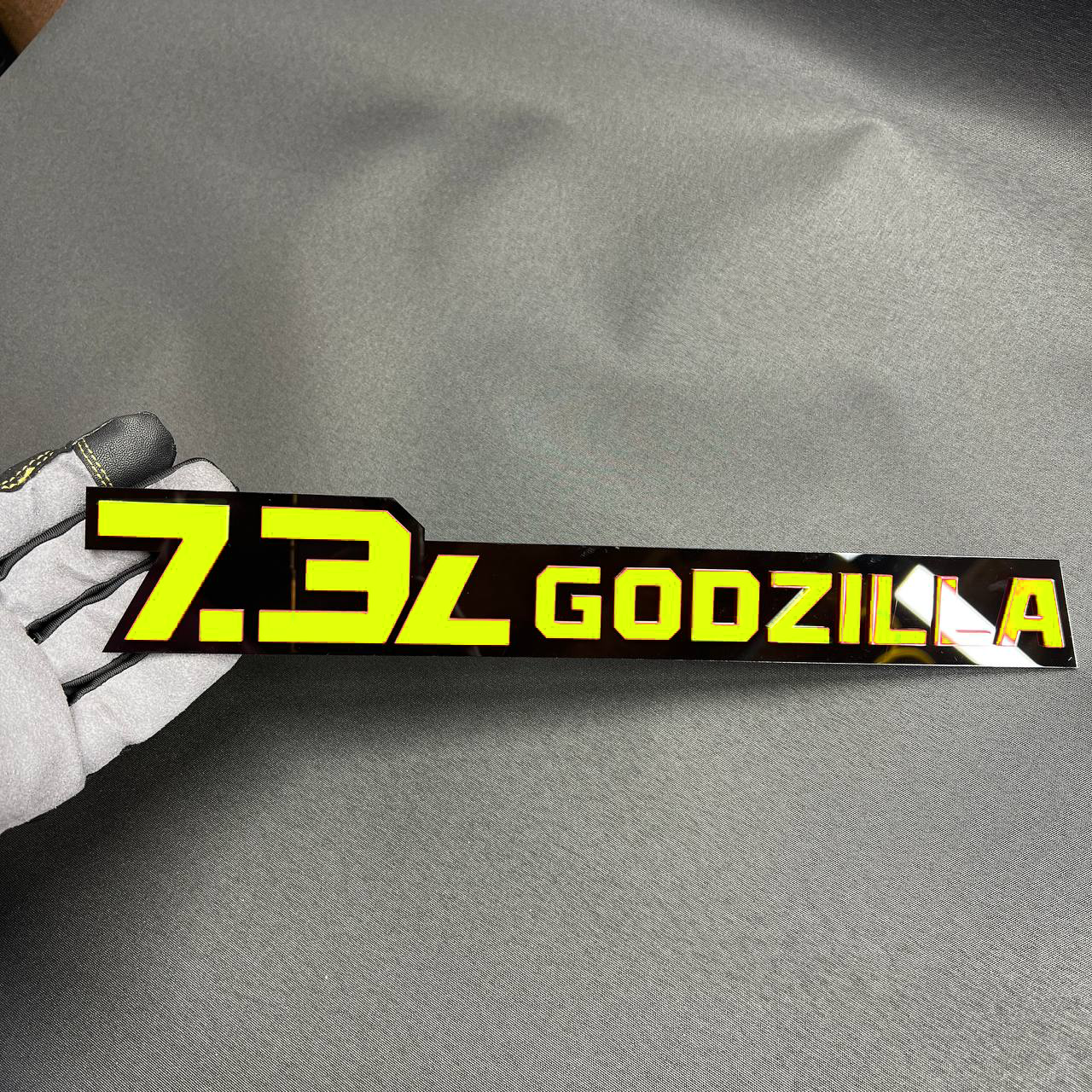 Black and pink 7.3L Godzilla acrylic decal badge for heavy-duty truck fender upgrade.