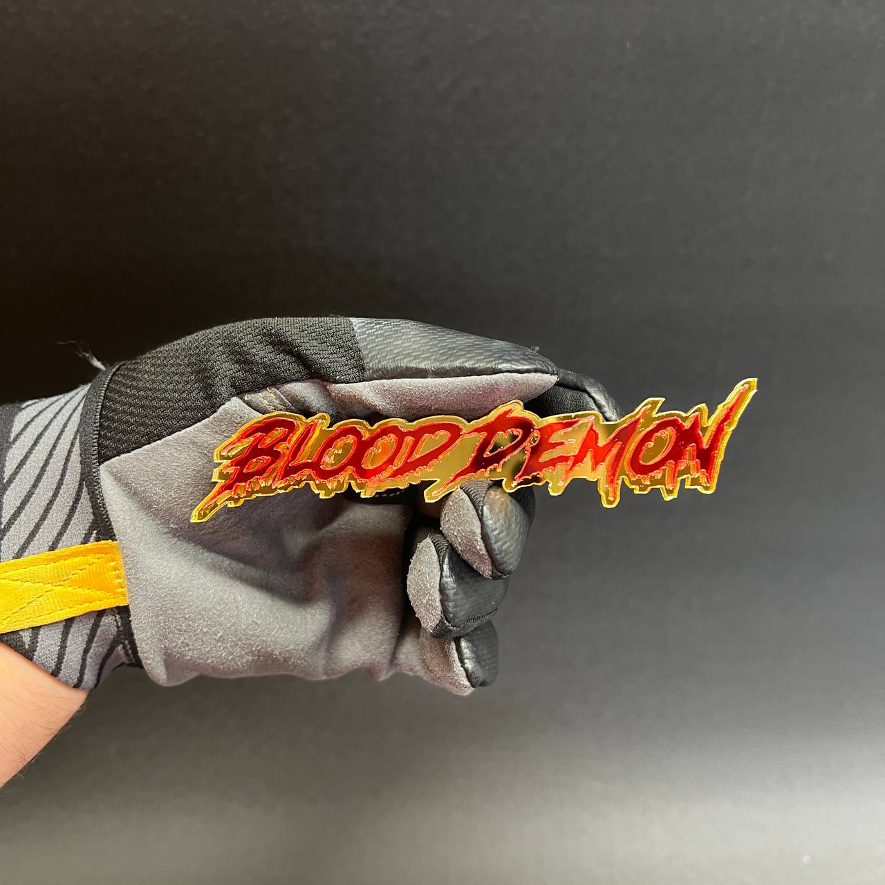 Red and gold acrylic automotive emblem with graffiti inspired dripping script lettering style