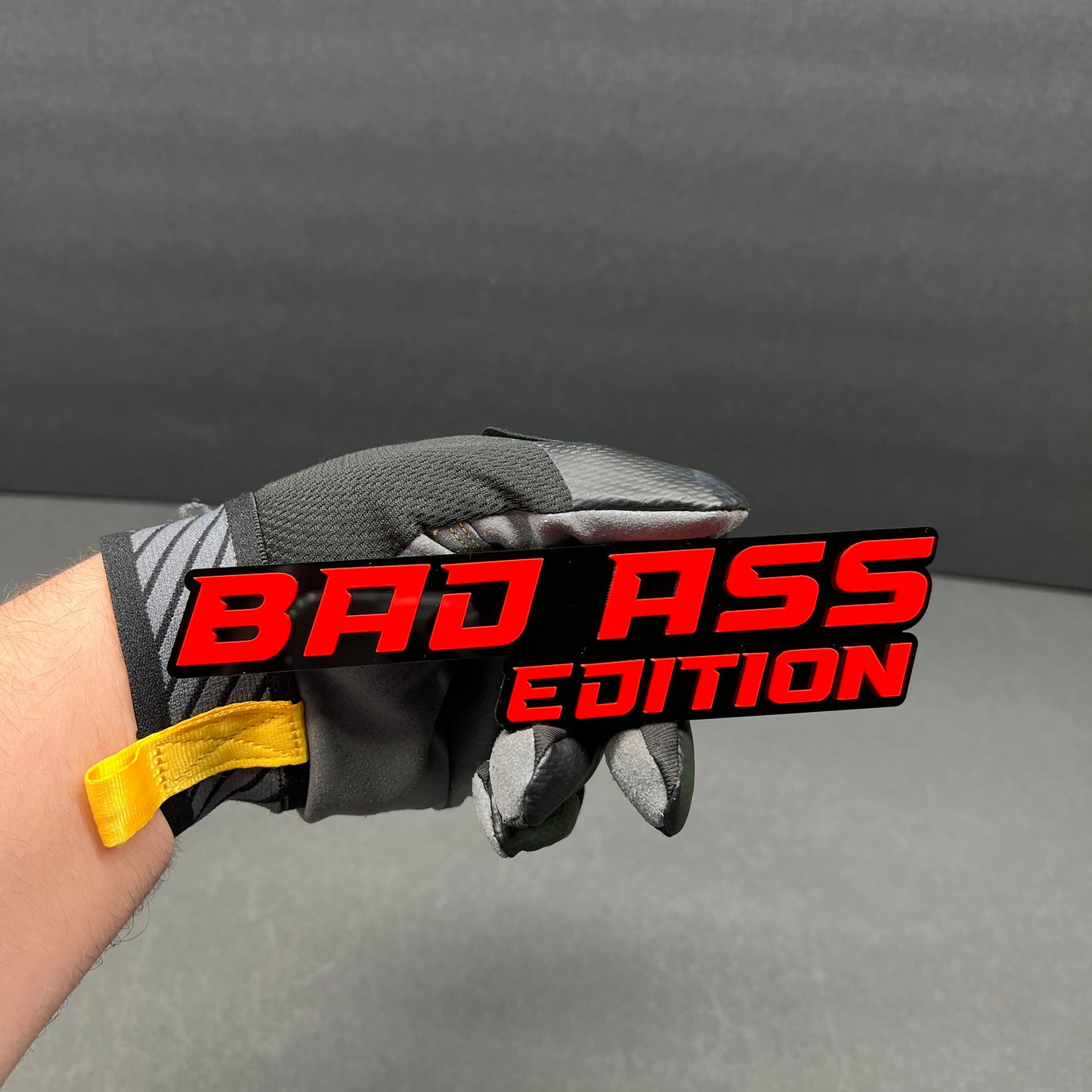 Gloss black and red Bad Ass Edition custom text emblem for personalized vehicle styling.