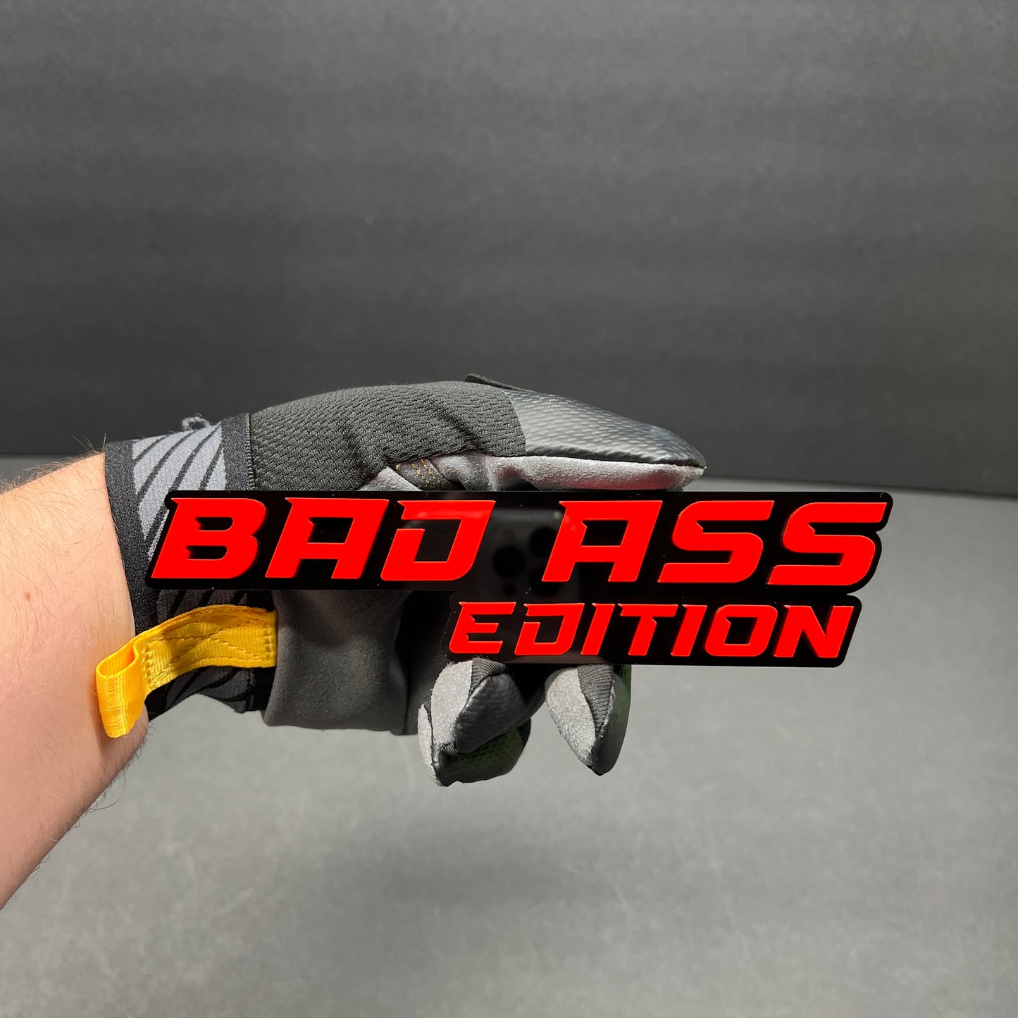 Premium Bad Ass Edition automotive emblem with bold red lettering on black backing.