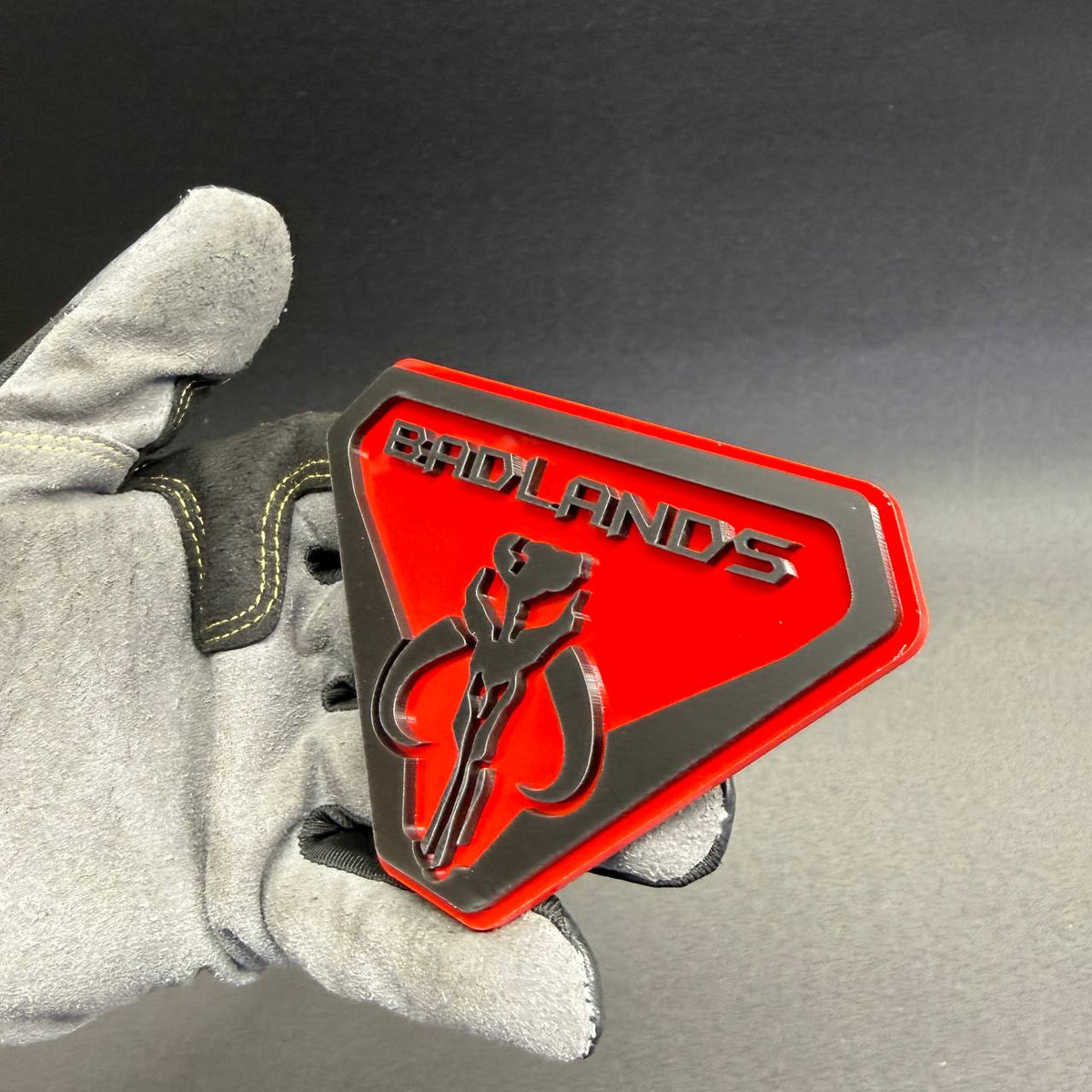 Badlands Mythosaur skull badge featuring a geometric shield shape, raised black detailing and bright red background for 4x4 vehicles.