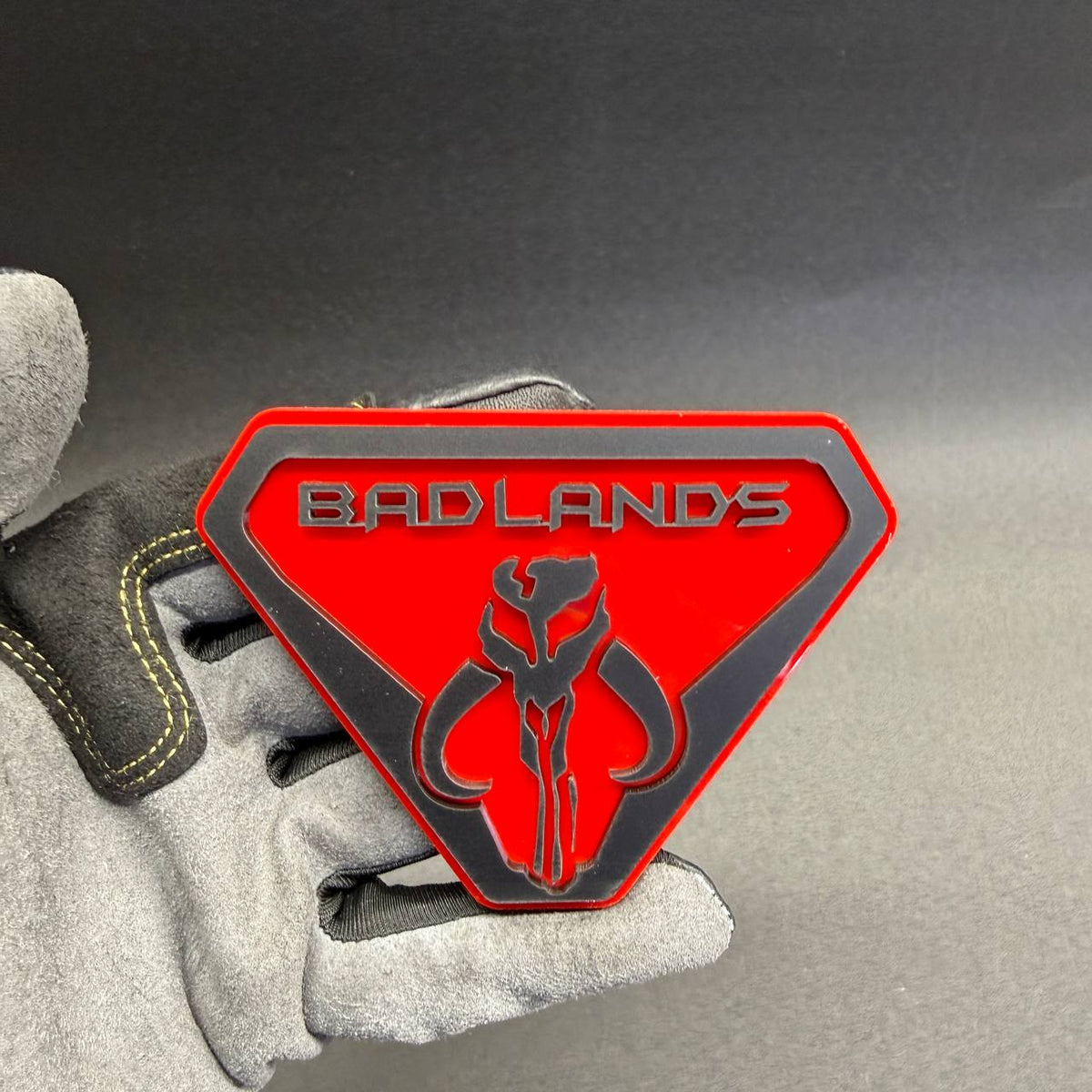 Custom Badlands Mythosaur car badge featuring a red background, black skull design and raised lettering for trucks, SUVs and off-road vehicles.