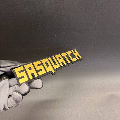 Bigfoot inspired vehicle emblem with black base and yellow top layer