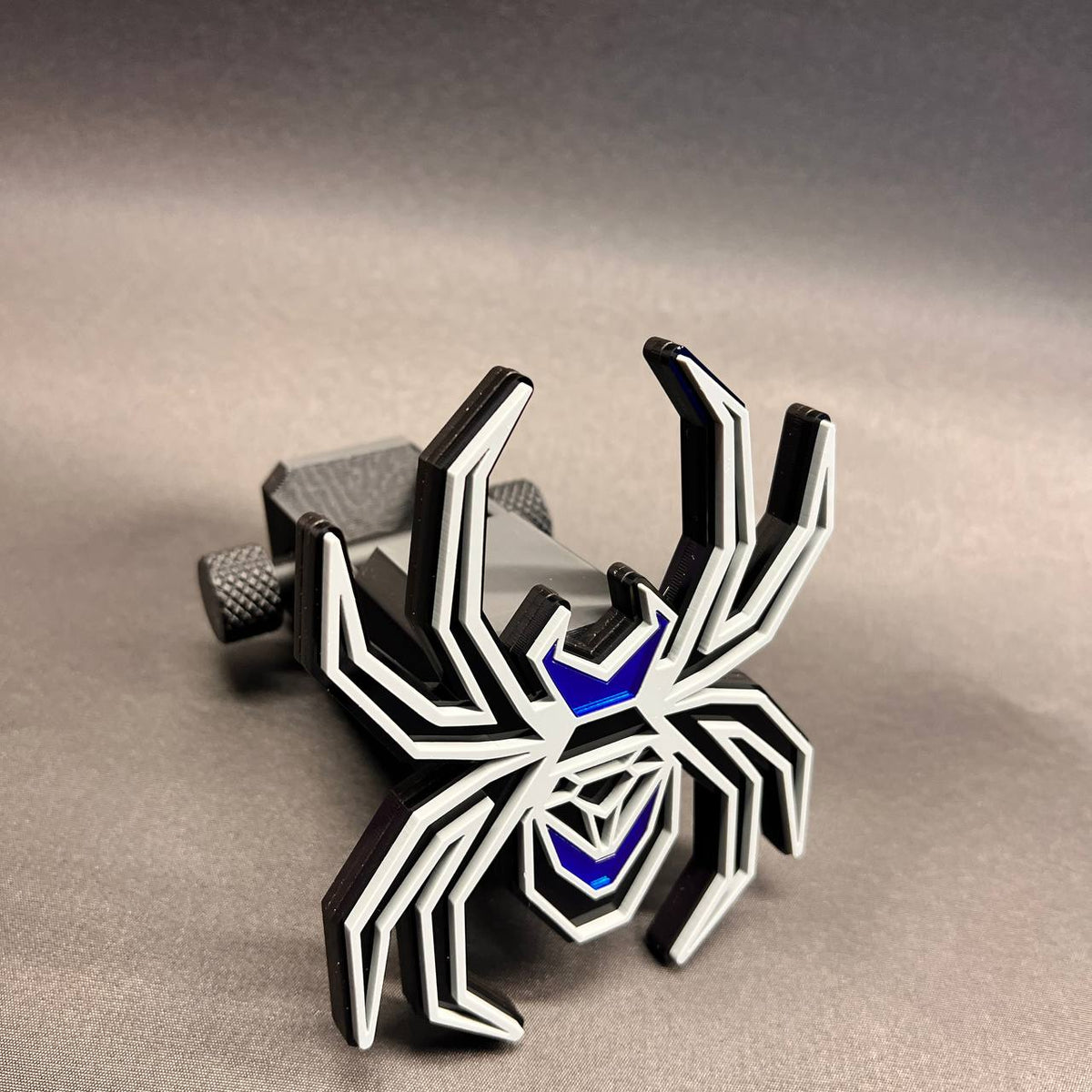 Custom Black Widow car badge style hitch cover in black, gray, and mirror blue.