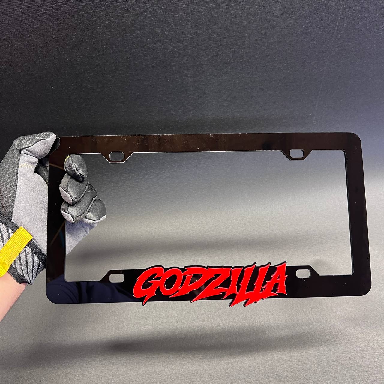 Godzilla car exterior frame in black with red raised lettering for license plate