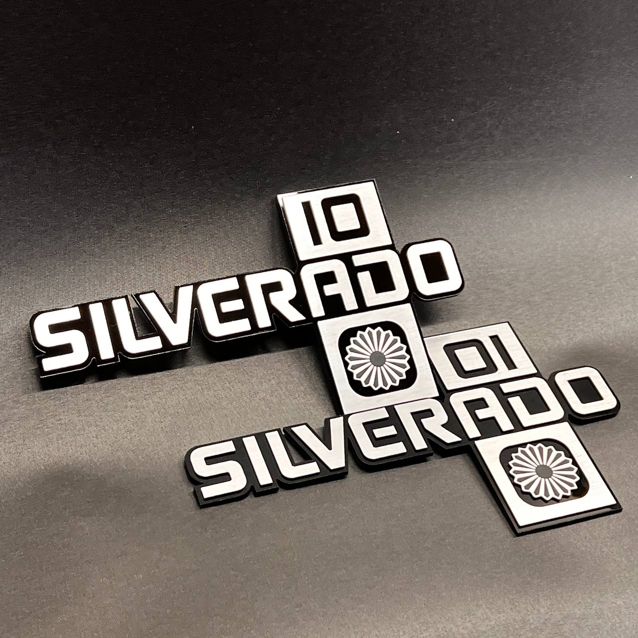 Silverado truck side badge with bold raised lettering and decorative icon