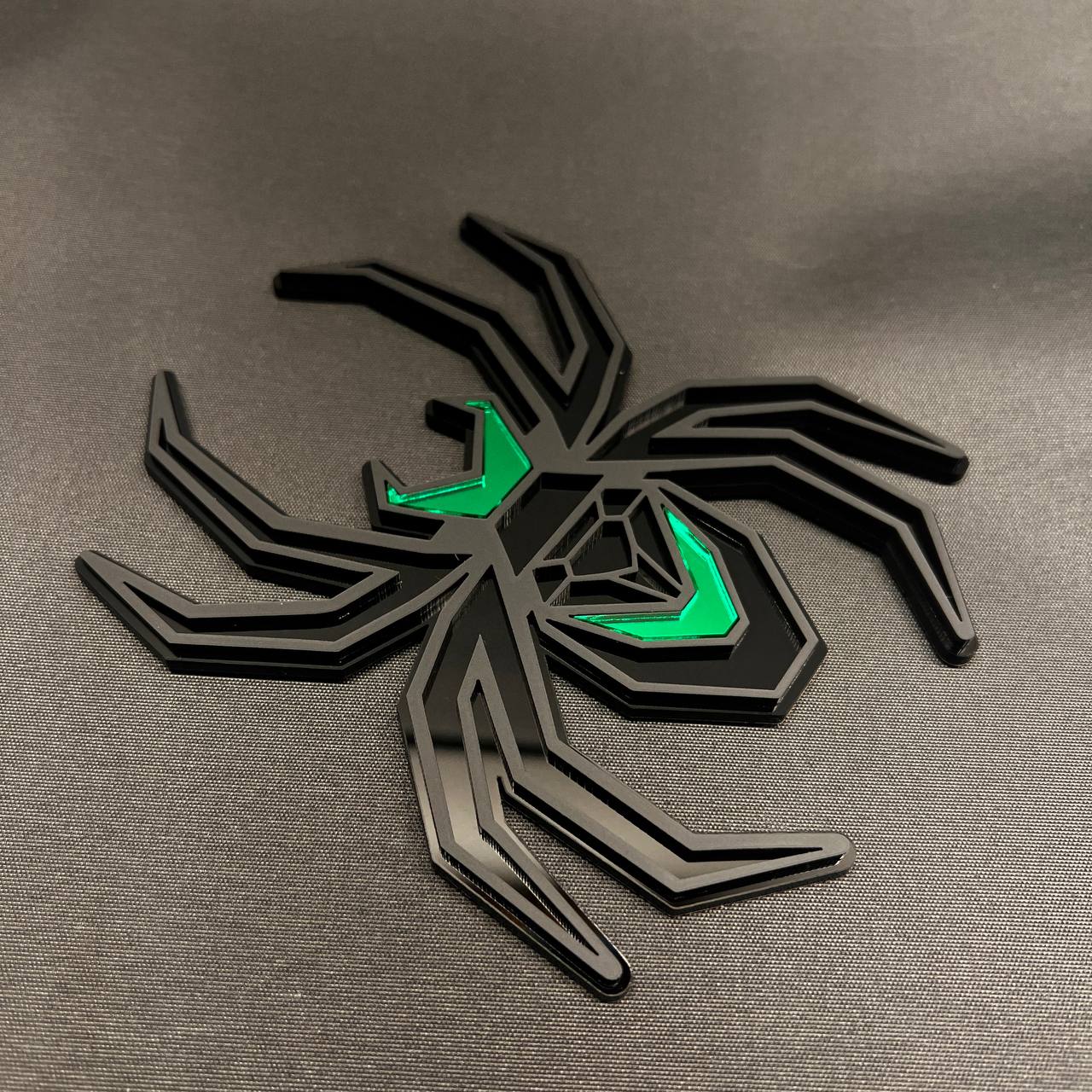 Black Widow spider receiver hitch cover with matte black finish and vivid green detailing.