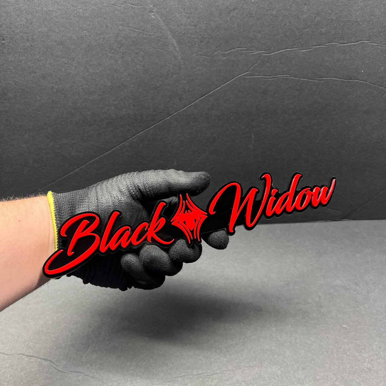 Detailed view of Black Widow custom car emblem made from layered automotive acrylic