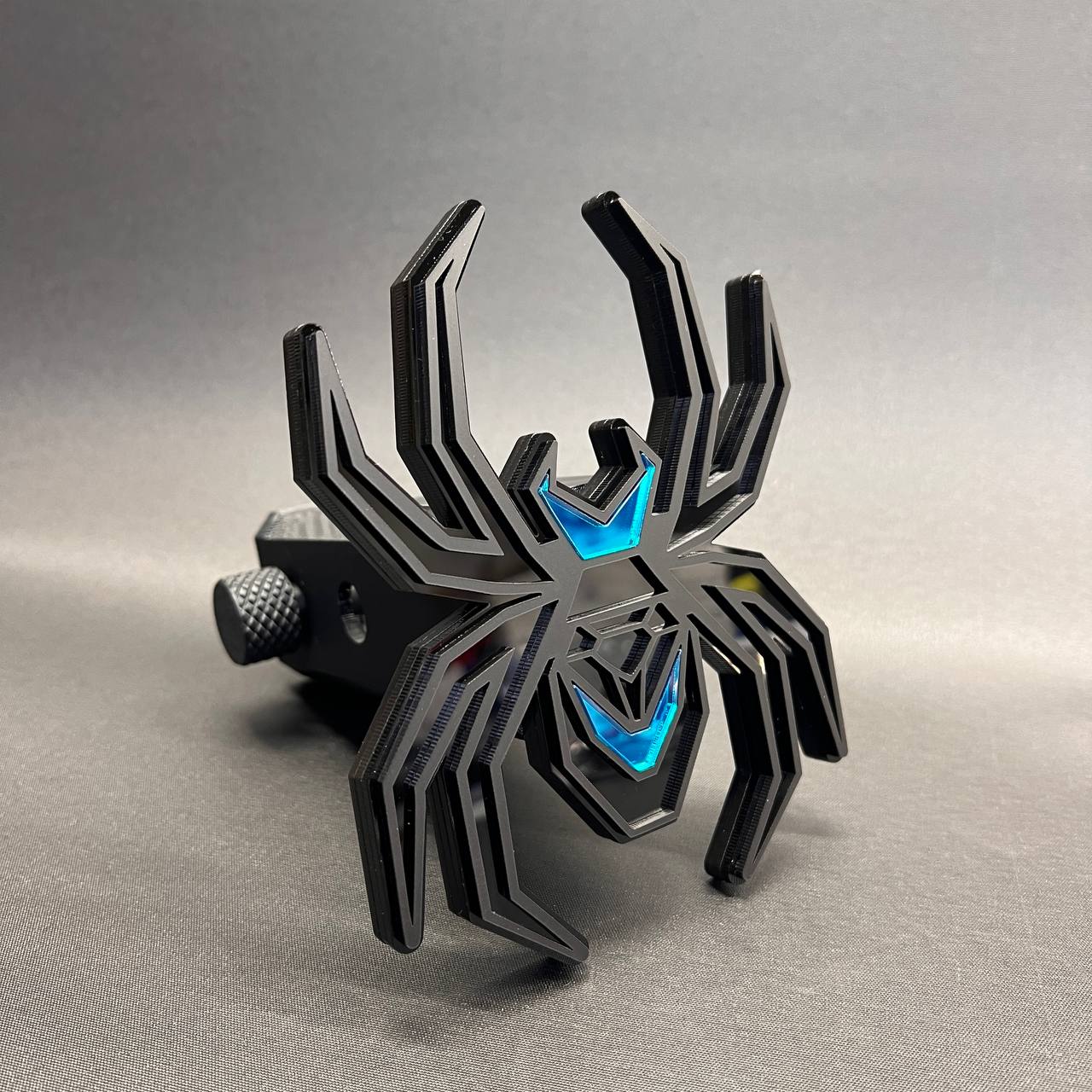 Layered black widow spider hitch plug cover with blue accent design