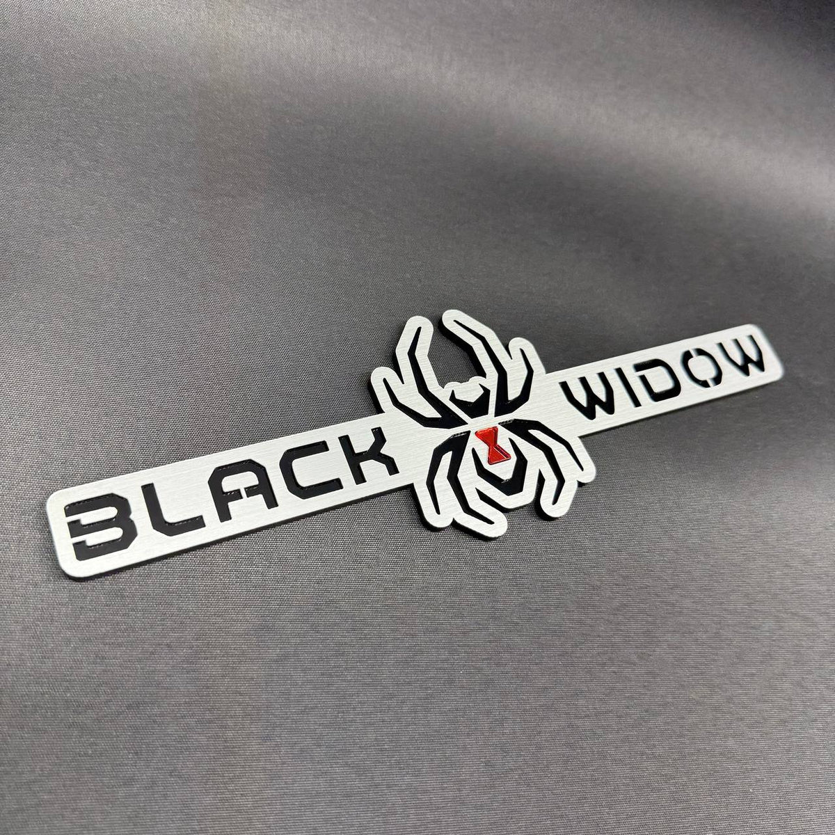 Black Widow automotive text emblem featuring a detailed spider design for custom car and truck styling.