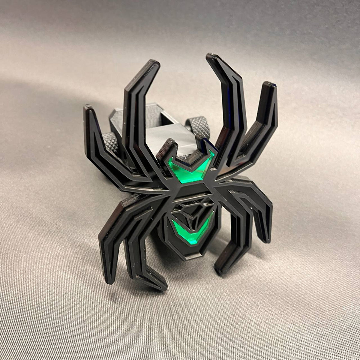 Decorative Black Widow spider receiver hitch cover in black and green automotive styling.
