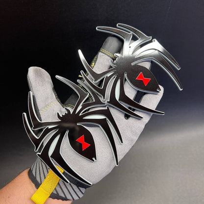 Decorative Black Widow spider vehicle badge pair shown on a gloved hand for size reference
