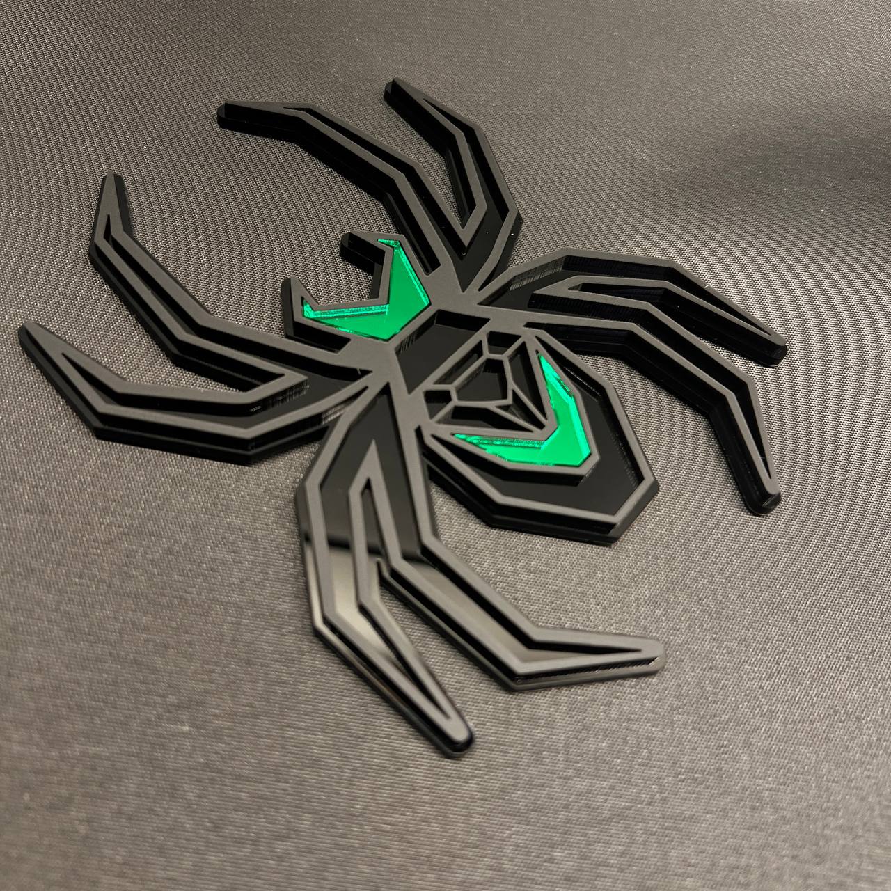 Black and green Black Widow hitch cover featuring a bold layered spider emblem design.