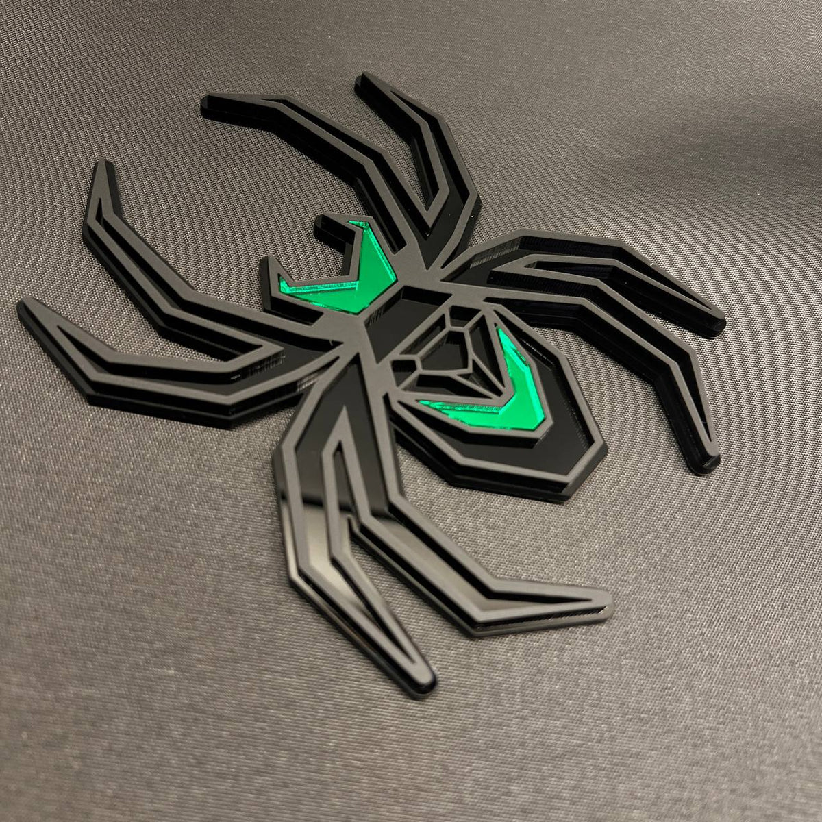 Black and green Black Widow hitch cover featuring a bold layered spider emblem design.
