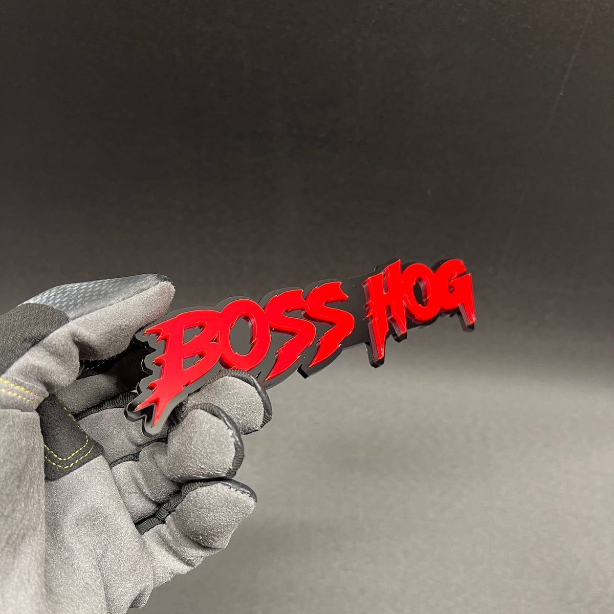 Custom Boss Hog car badge with red lettering on glossy black backing
