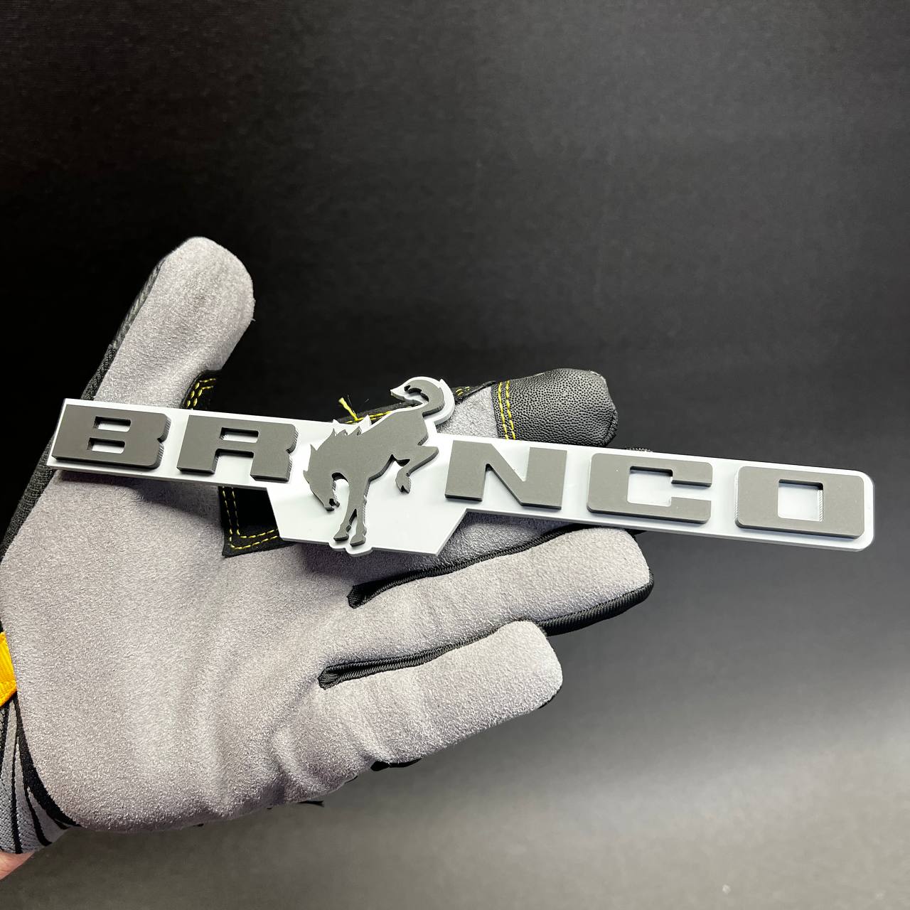 Bronco gray white car badge with raised lettering and horse center