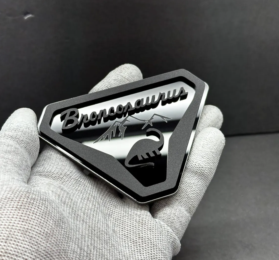 Close-up of Broncosaurus dinosaur emblem for Ford Bronco with mountain design and engraved details