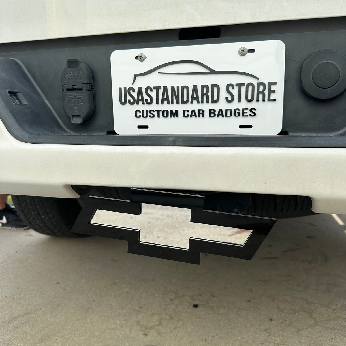 Black and silver Chevy Bowtie hitch cover emblem mounted on truck receiver