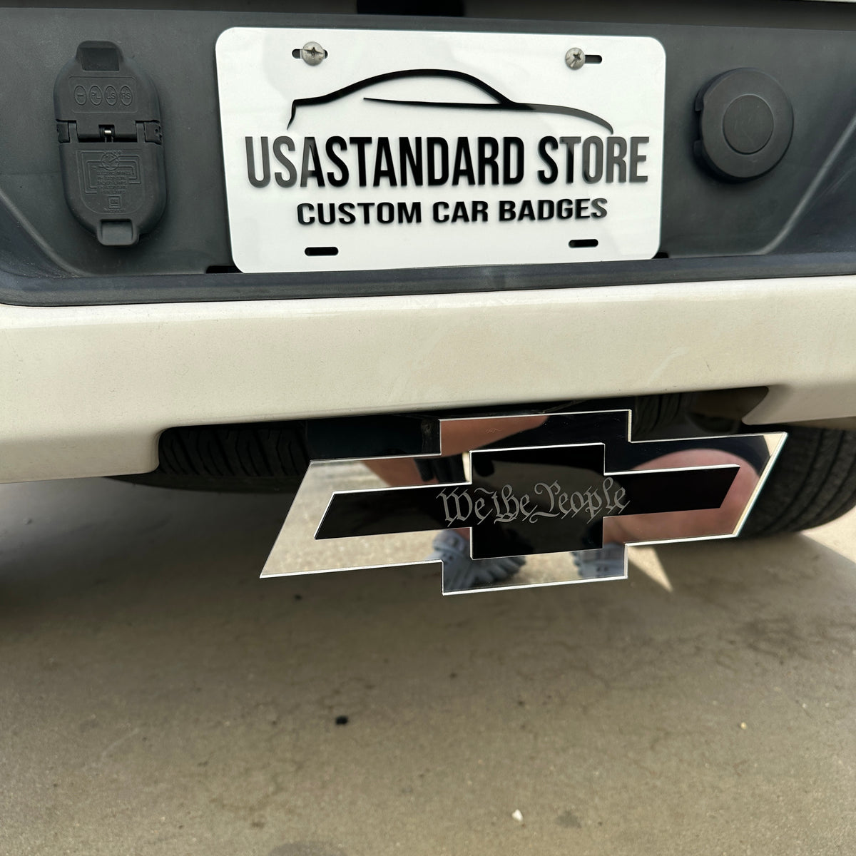 Silver and black Chevy hitch cover with We the People engraving