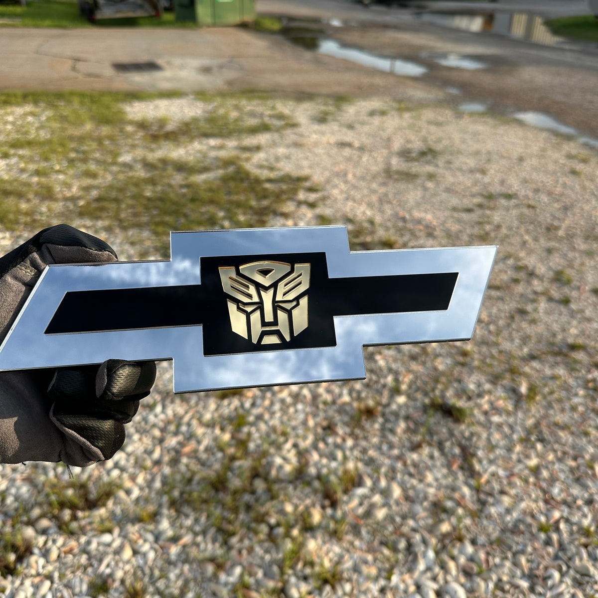 Silver and black Chevy Bowtie car badge with gold Autobot center logo