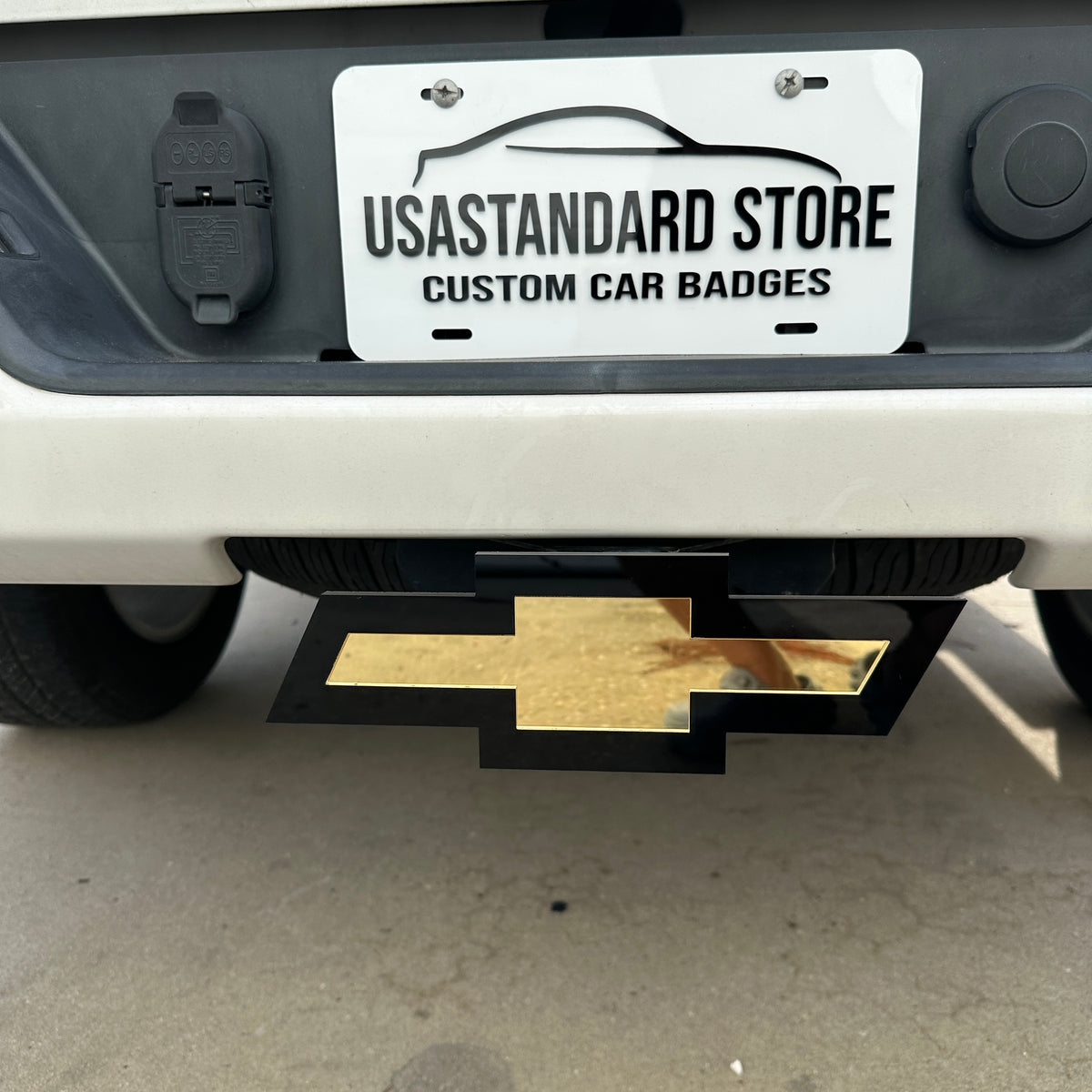 Gold Chevy Bowtie hitch cover emblem with black backing mounted on truck