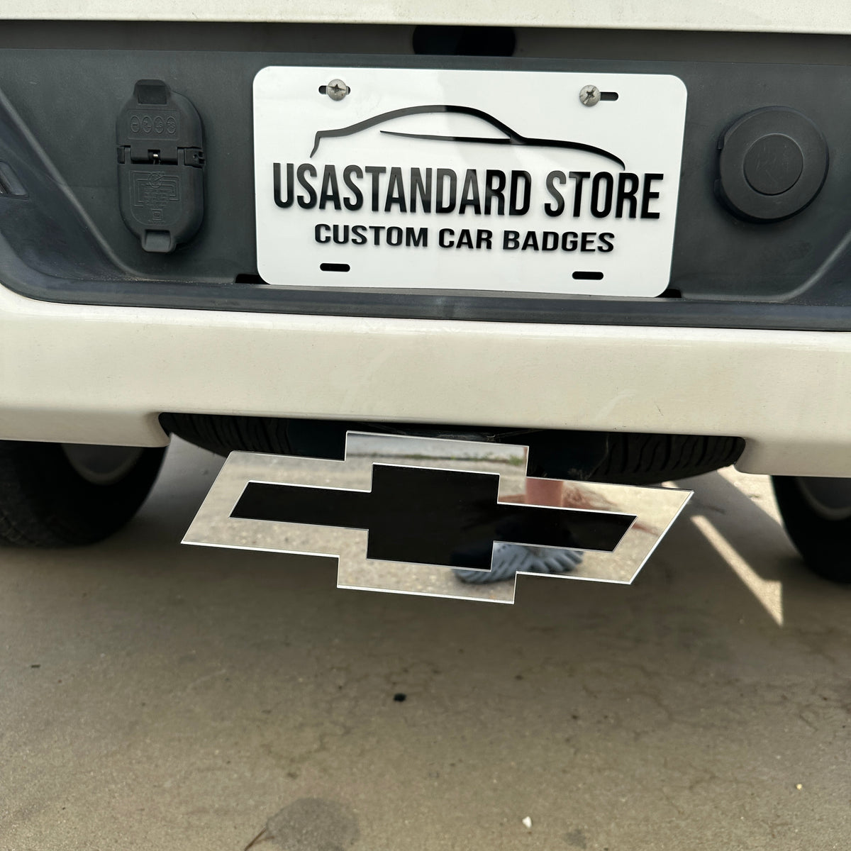 Silver and black Chevy Bowtie hitch cover emblem mounted on a truck receiver