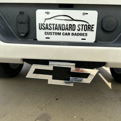 Silver and black Chevy Bowtie hitch cover emblem mounted on a truck receiver