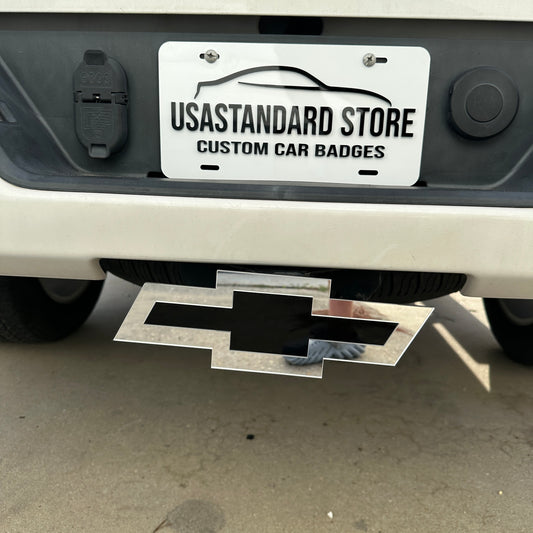 Silver and black Chevy Bowtie hitch cover emblem mounted on a truck receiver