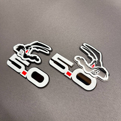 Ford F-150 Coyote 5.0 performance badge in gray and glossy black with red eye detailing and distinctive layered design.