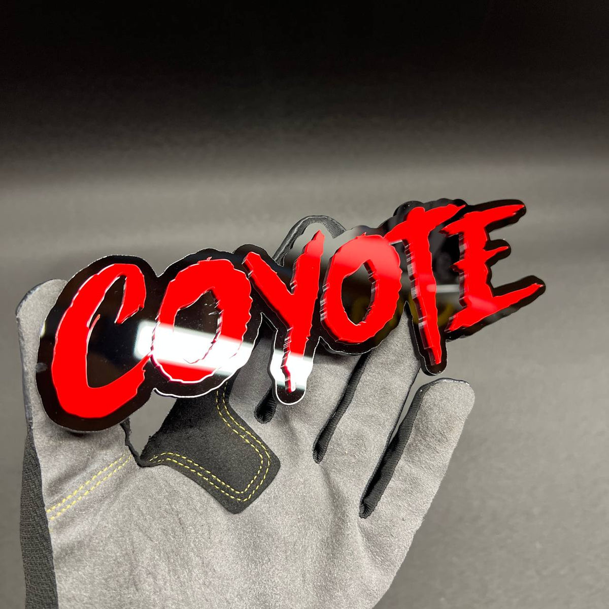 Custom COYOTE text automotive emblem with bold red lettering on black