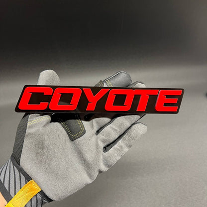 COYOTE RACING car emblem with red lettering on black base
