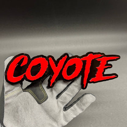 COYOTE text car badge with red lettering and black background automotive emblem