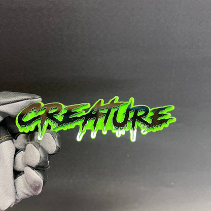 Drip style CREATURE car badge with green outline and black top layer