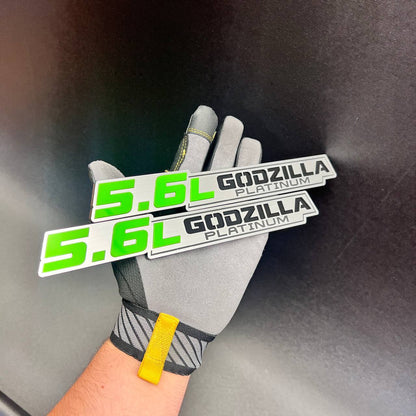 Green and silver 5.6L Godzilla Platinum fender emblem shown as a matching pair