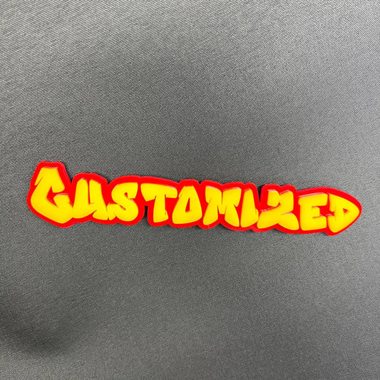 Custom graffiti font car badge with red outline and yellow lettering.