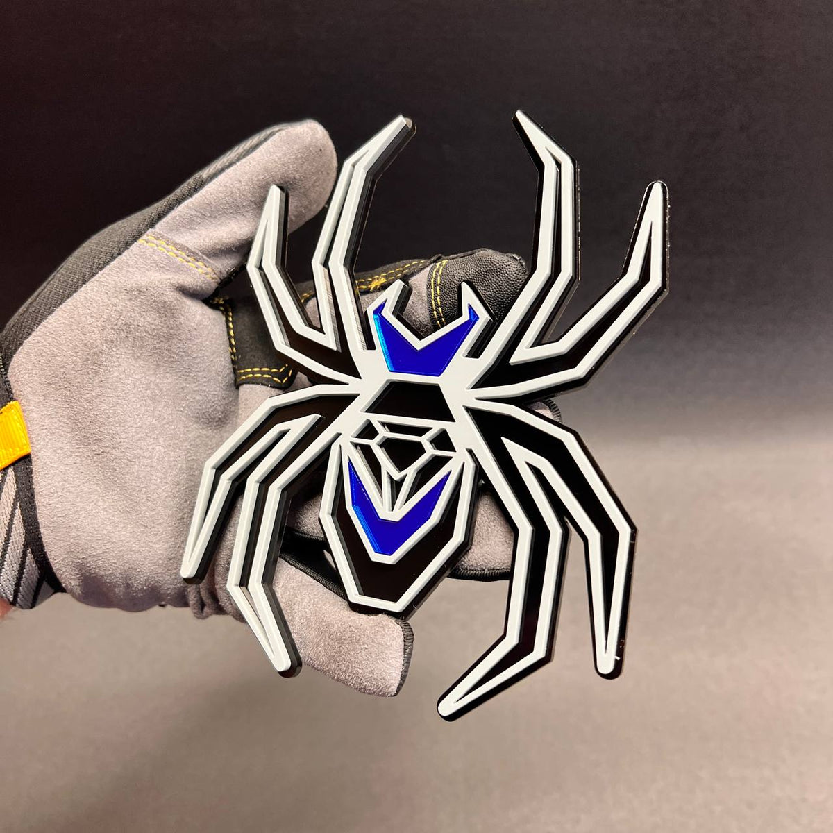 Black Widow automotive emblem featuring black and gray layers with mirror blue accent panels.
