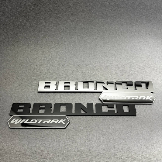 Black Bronco Wildtrak badge with layered lettering and trim emblem