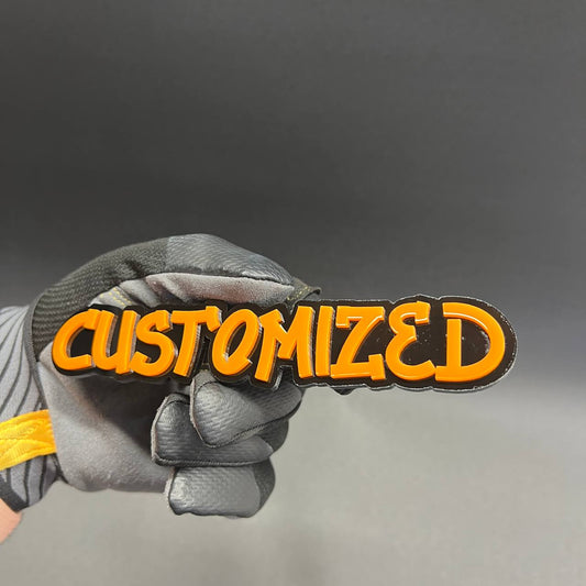 Custom graffiti font car badge with orange lettering and black base.