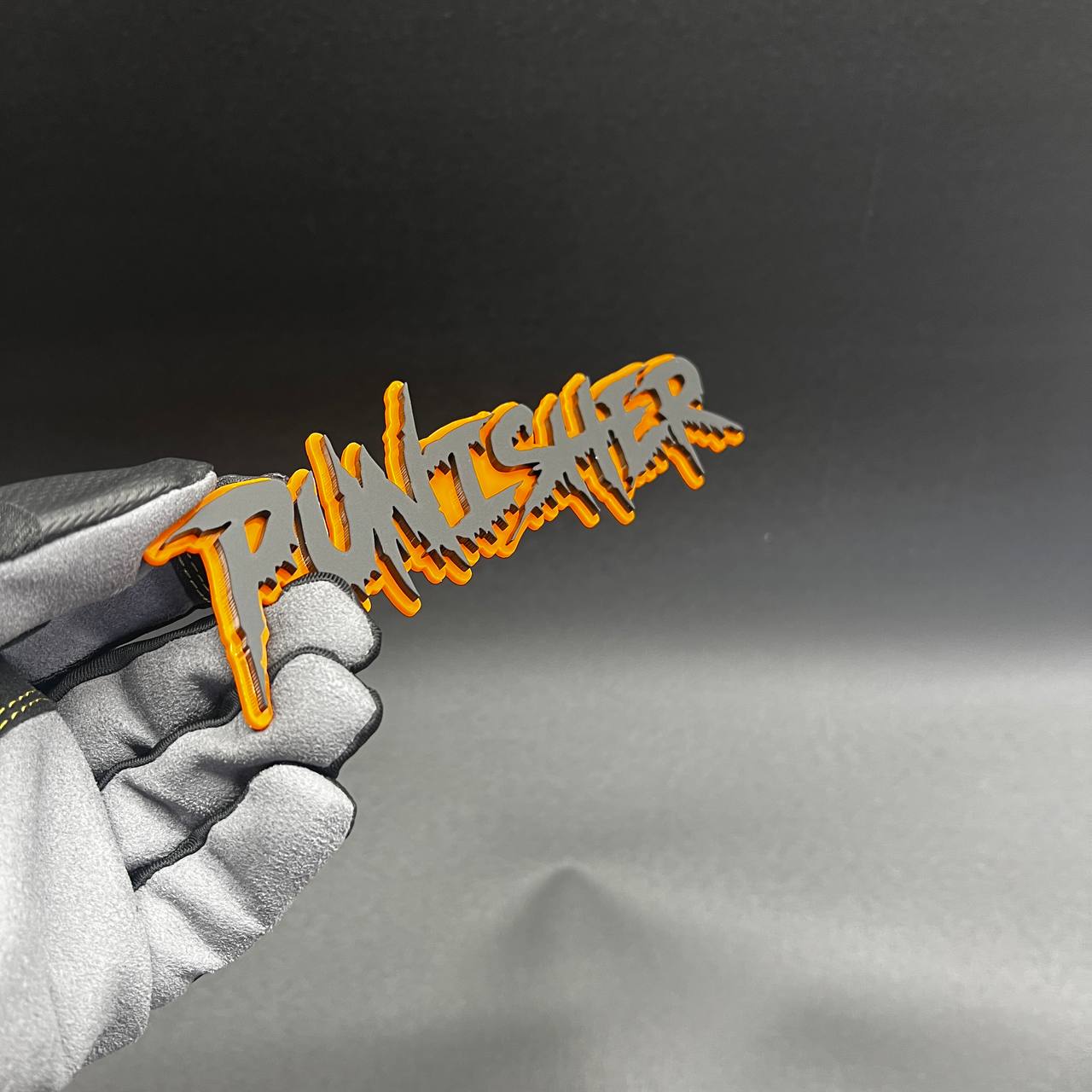 Silver and orange Punisher fender emblem with sharp dripping letter design