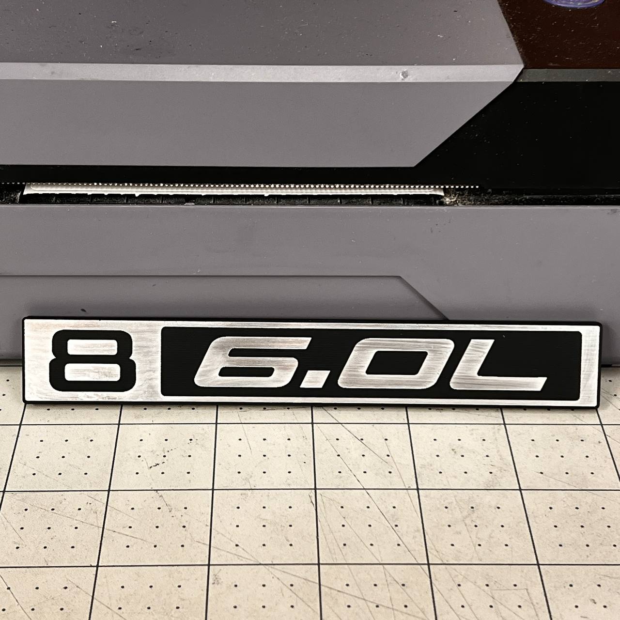 Silver and black B 6.0L Chevy C10 truck badge with billet style finish.