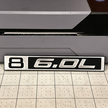 Silver and black B 6.0L Chevy C10 truck badge with billet style finish.