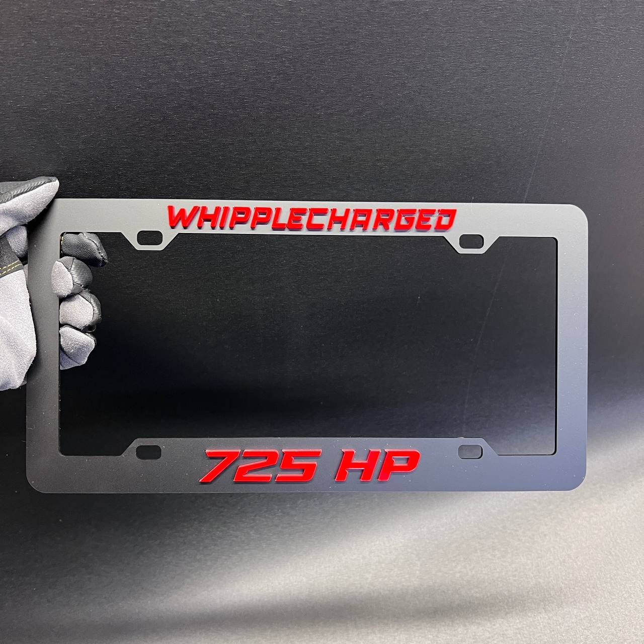 Black car license plate frame featuring Whipplecharged and 725 HP red lettering