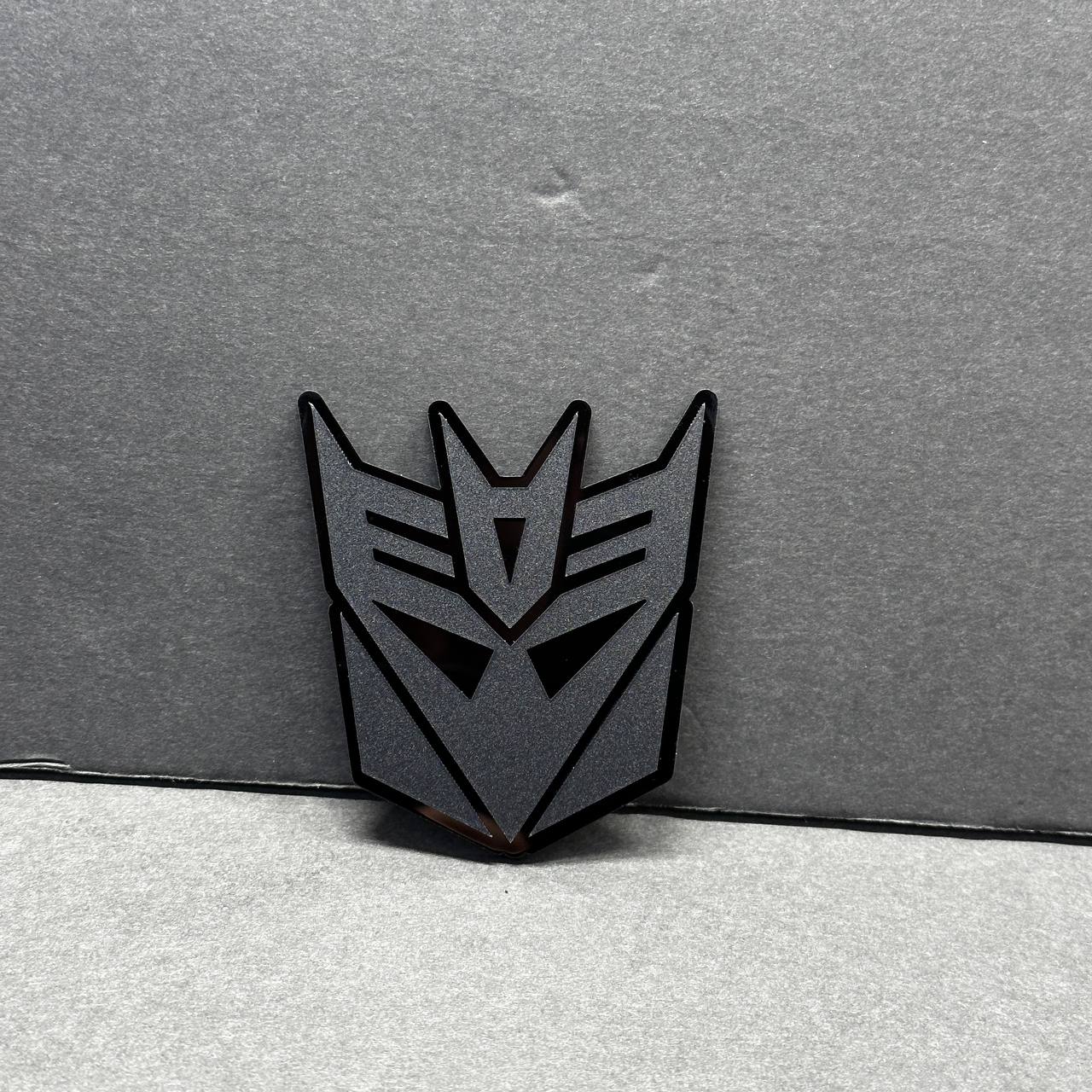 Close-up of Transformers Decepticon emblem – 3D matte black acrylic car badge
