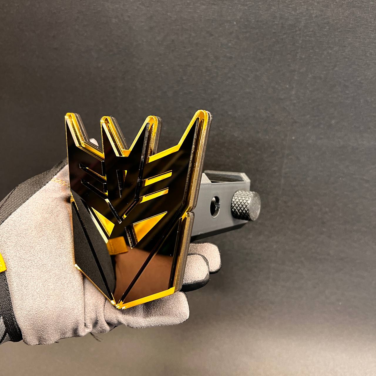 Black gold Decepticon logo hitch cover for truck, SUV, and car exterior.