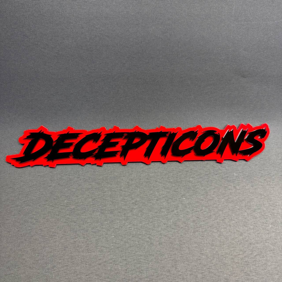 Transformers Decepticon text car badge featuring bold black jagged lettering on a bright red background, custom Ford F150 fender emblem accessory.