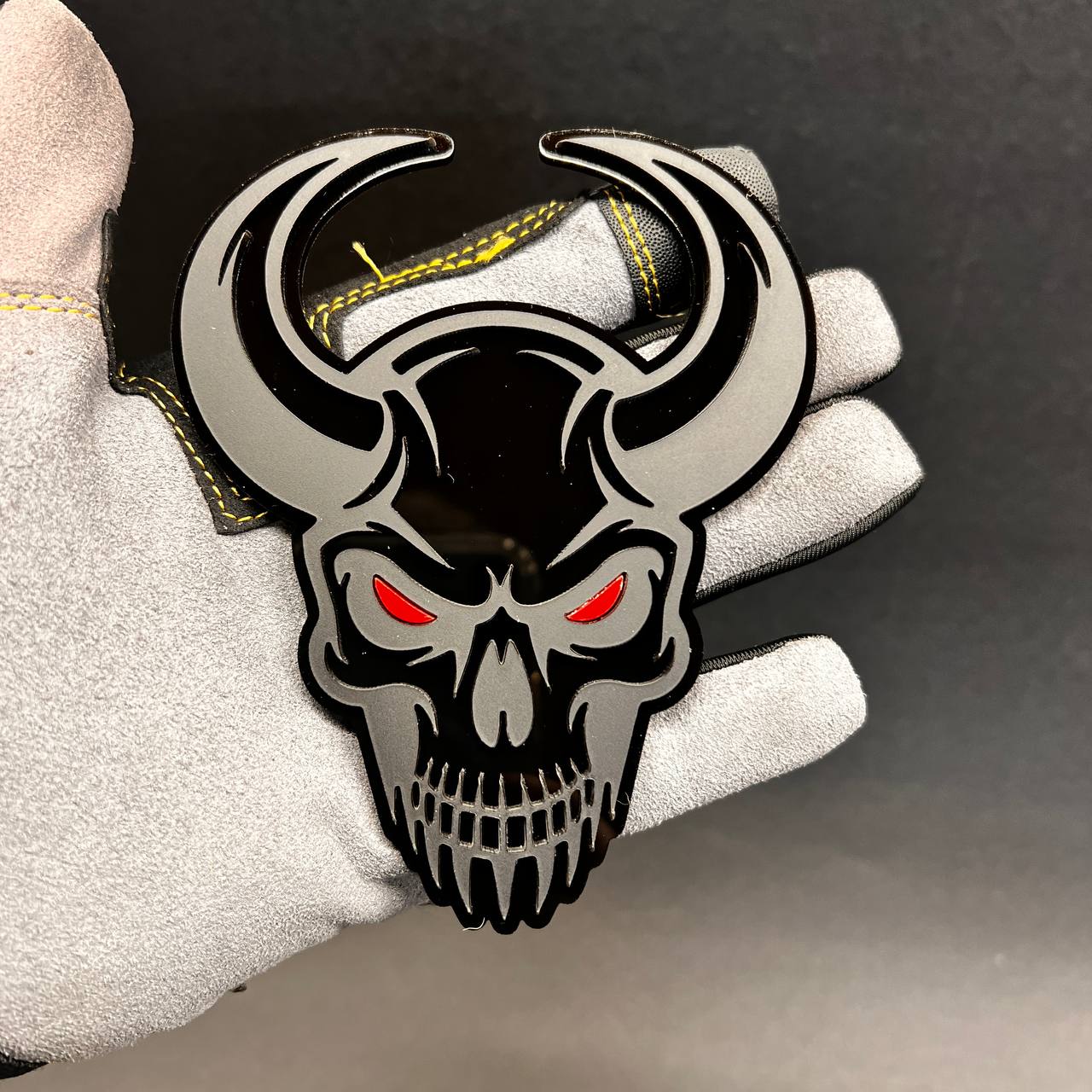 Demon Skull car badge with black and gray layered design and red eyes